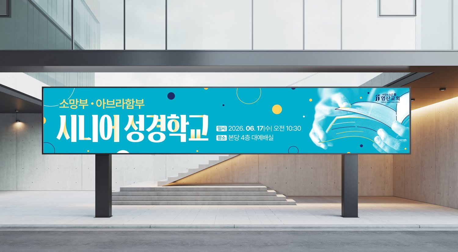 건물 앞 게시대 연출 — 청록 바탕과 흰 타이틀의 명도 대비가 멀리서도 또렷합니다.