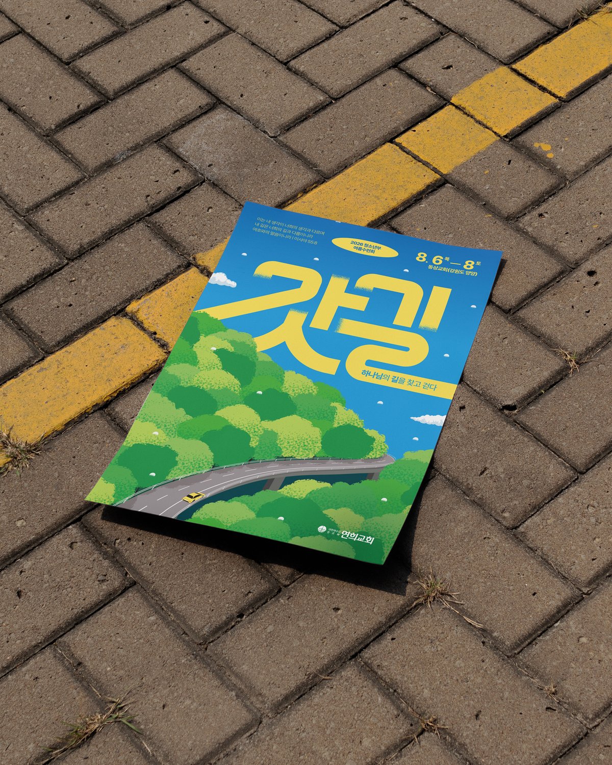 보도블록 위 낱장 — 바닥의 노란 차선 도색이 포스터의 노랑과 나란히 놓입니다.