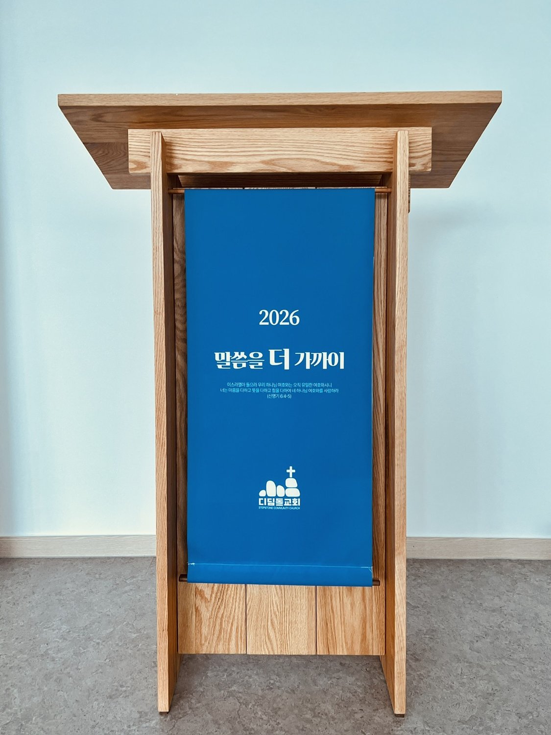 디딤돌교회 반듯강대상 — 상판 폭 75센티미터에 앞면을 막고, 푸른 배너에 교회 표어를 담은 완성 정면.